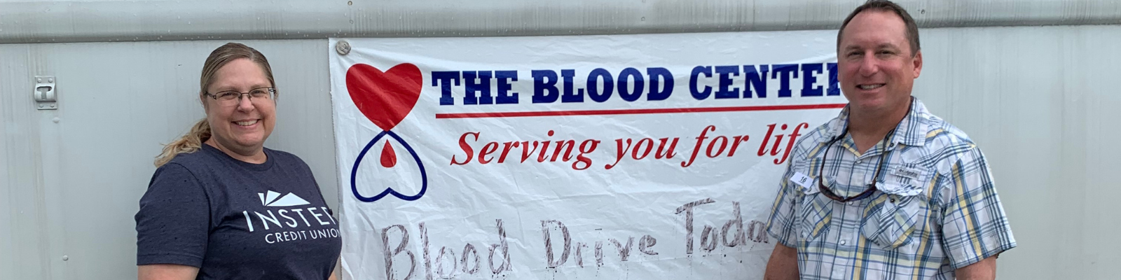 Man and woman standing in front of blood drive sign