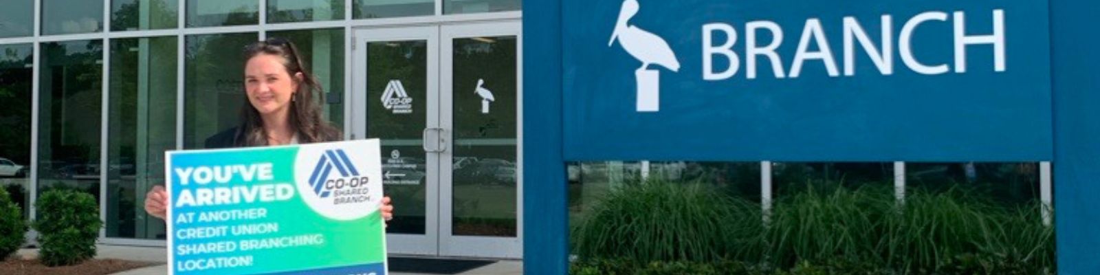Woman holding sign "you've arrived at another credit union shared branching location"